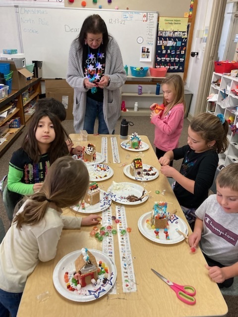 Ms. Julia helps the elementary students get in the Christmas spirit by making gingerbread houses.