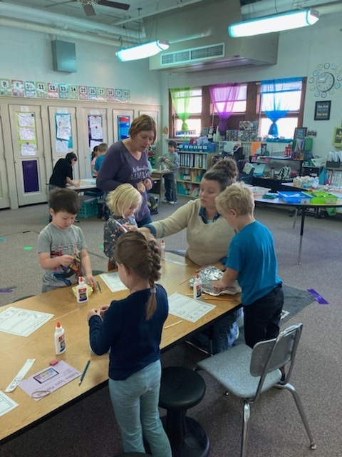 Ms. Miranda helps elementary students make their Mayflower ships at Thanksgiving. 
